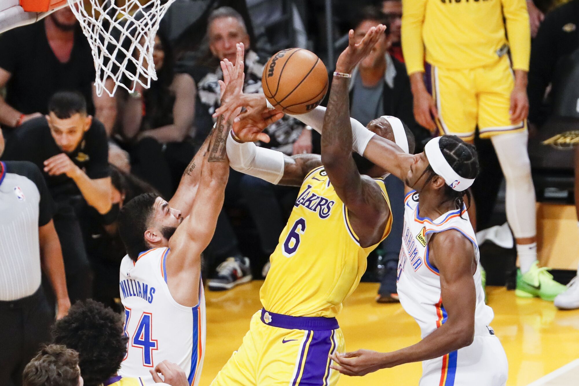 Lakers forward LeBron James goes up for a shot while fouled by Thunder guard Shai Gilgeous-Alexander.