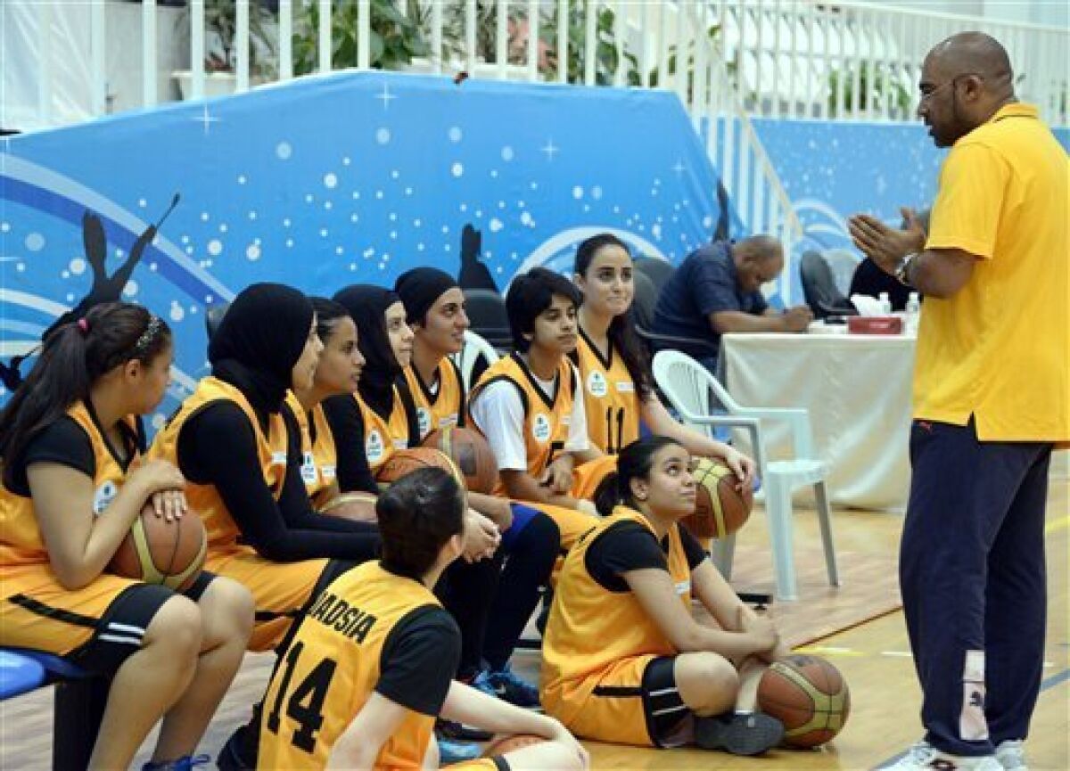 Kuwait's Qadsiya Club women basketball team listen to their coach, during the Women's Games, at Salwa Al Sabah Sports Center in Qurein, Kuwait, Thursday, May 9, 2013. The event is part of a new initiative launching sports leagues for women, including basketball, table tennis and athletic leagues for the first time in Kuwait illustrating how the landscape for women athletes is improving across the Persian Gulf where hard-liners have long opposed women playing sports. (AP Photo/Gustavo Ferrari)