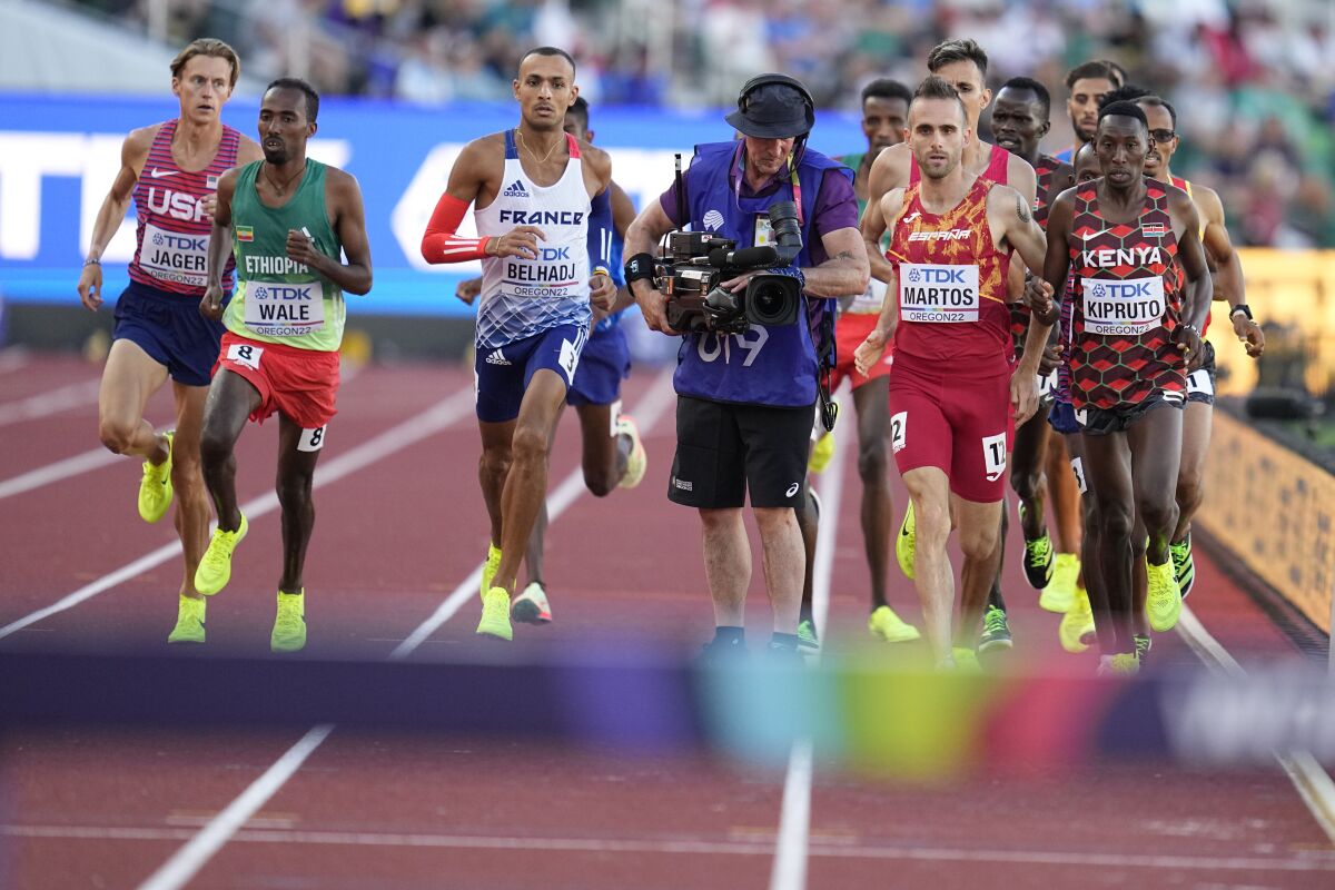 Men compete and move around a camera person on the track during the men's 3000-meter steeplechase final at the World Athletics Championships on Monday, July 18, 2022, in Eugene, Ore. (AP Photo/Ashley Landis)