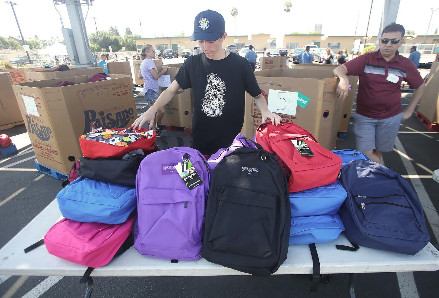 Reece Jones, a Huntington Beach High student, organizes colorful backpacks during the Share Our Selves (SOS) 23rd Annual Back to School Distribution on Saturday, at the BESST Center in Costa Mesa. The SOS Back to School Program provides approximately 4,000 backpacks filled with school supplies to Orange County children in need.