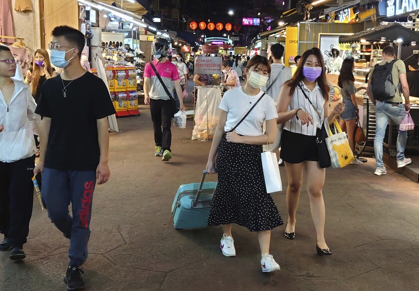 People wear face masks at a night market
