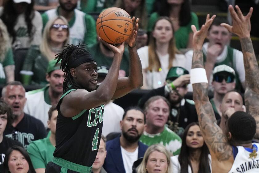 Boston Celtics guard Jrue Holiday takes a shot over Dallas Mavericks forward P.J. Washington.