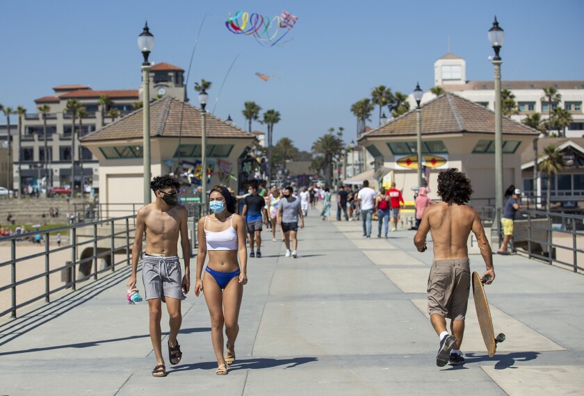 People walk along the Huntington Beach Pier Tuesday after it opened for the first time since March.