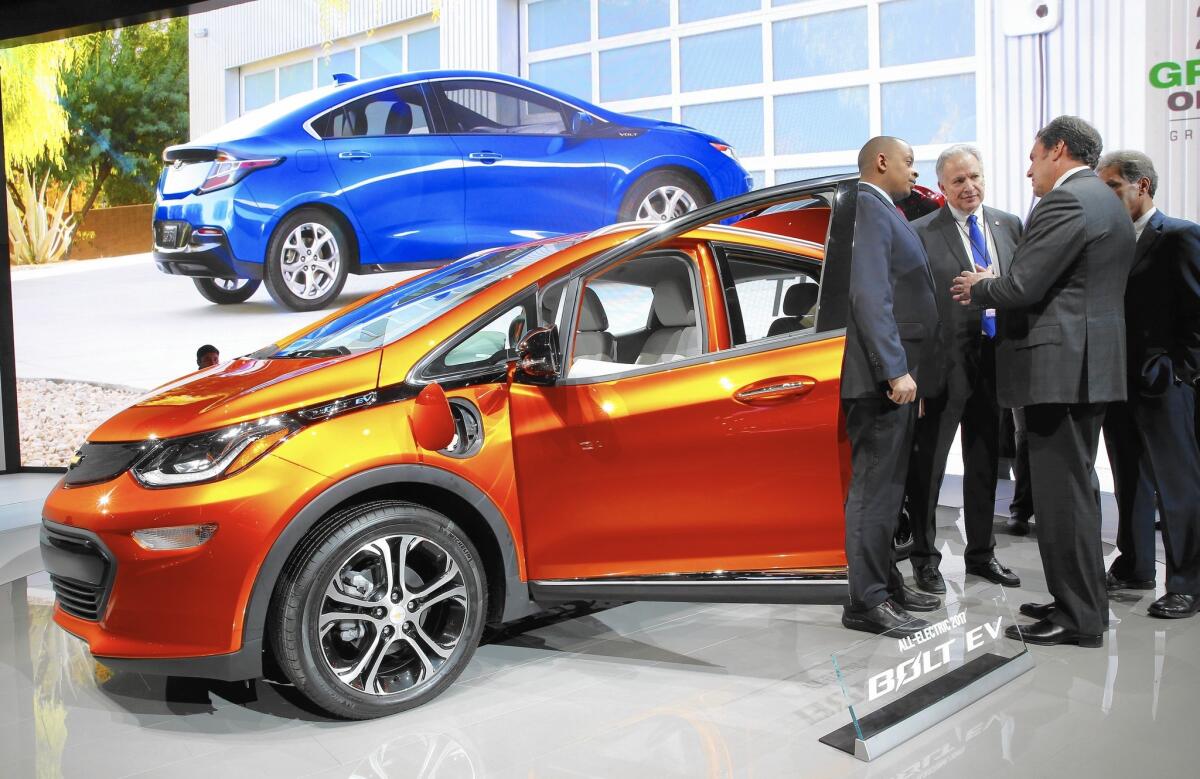 Transportation Secretary Anthony Foxx, left, and NHTSA Administrator Mark Rosekind listen to Mark Reuss of General Motors talk about the 2017 Chevrolet Bolt electric vehicle at the Detroit auto show.