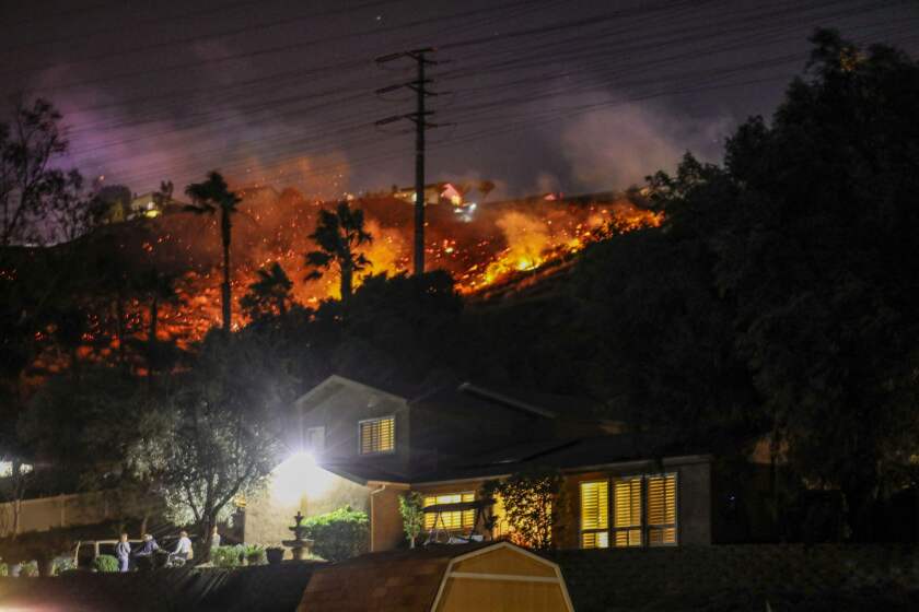 A brush fire burns near houses along Willow Glen Road in El Cajon, California.