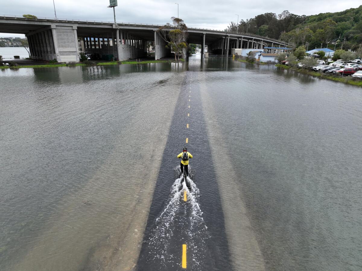 An aerial picture shows a a cyclist riding through a flooded bike path in Mill Valley during a king tide in 2022.