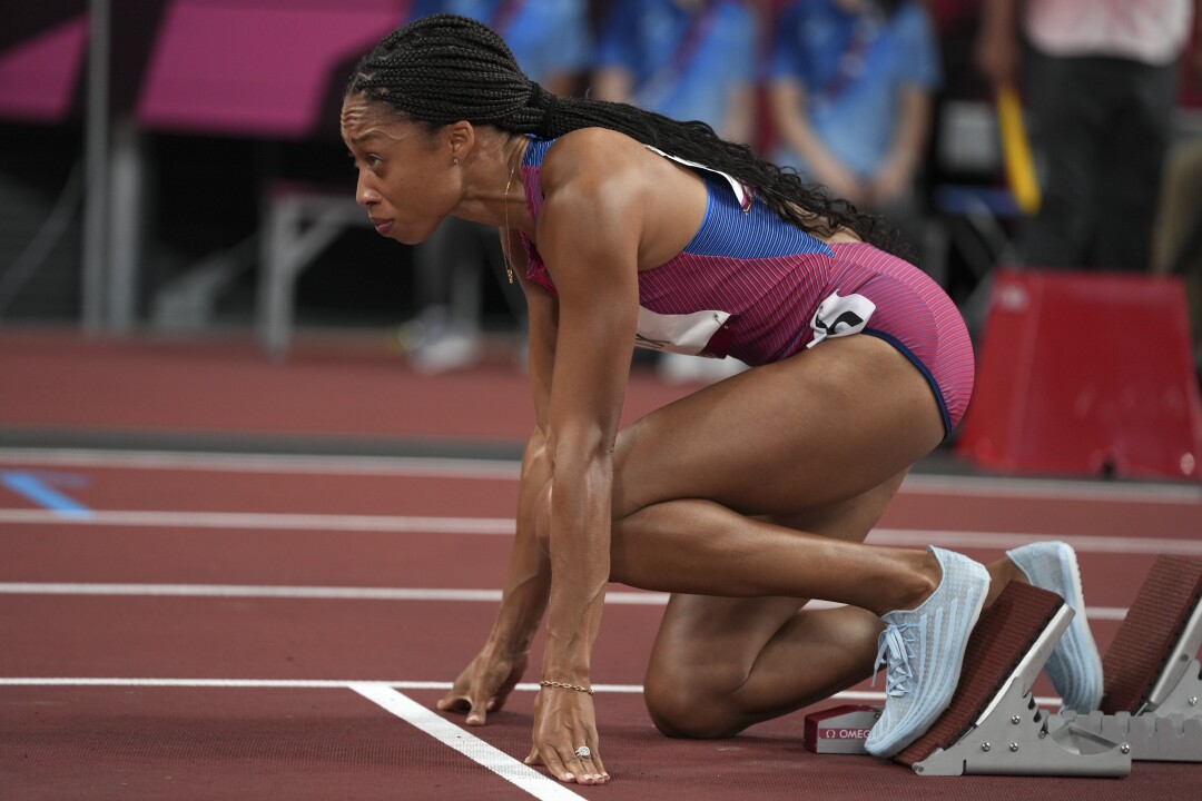 Allyson Felix se agacha nos blocos de largada enquanto se prepara para começar a semifinal.
