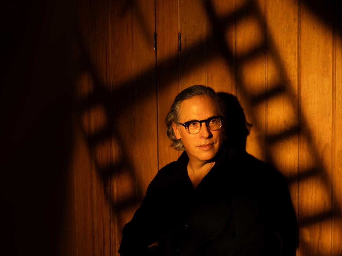Cinematographer Rodrigo Prieto is shot under a warm light with shadows of a film frame behind him.