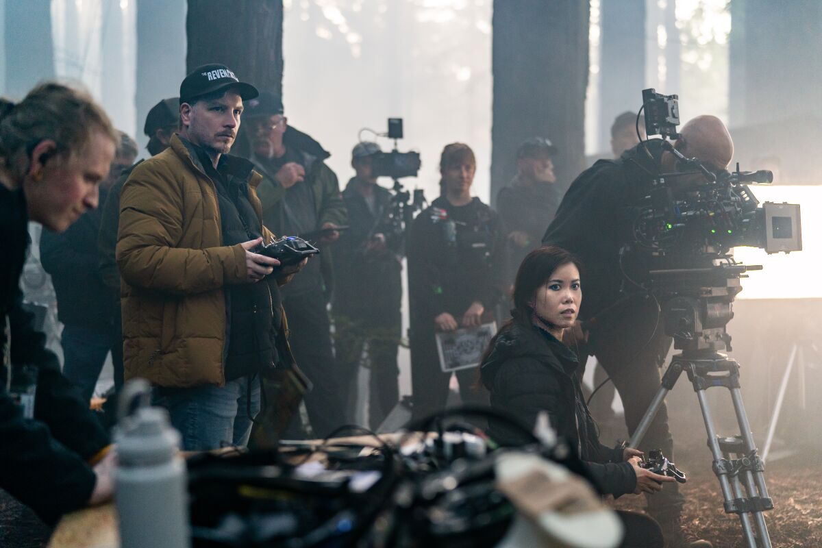 Adrien Morot and Kathy Tse are near several people and a camera on set.