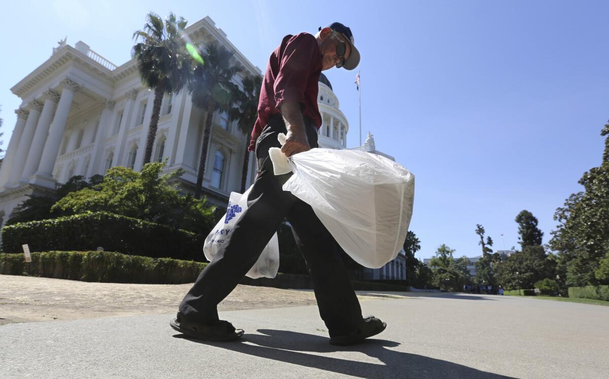 A man carries plastic single-use bags past the state Capitol in Sacramento.