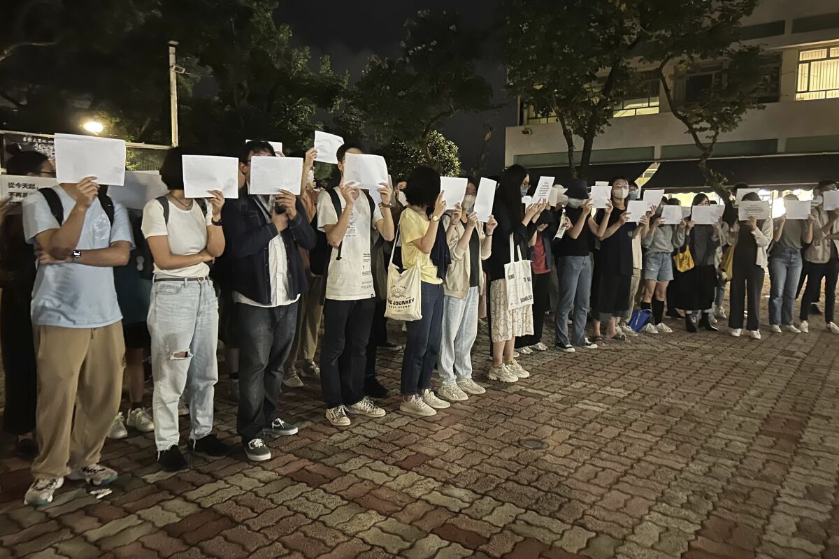 Protesters hold up blank white papers during a commemoration for victims of a recent Urumqi deadly fire 