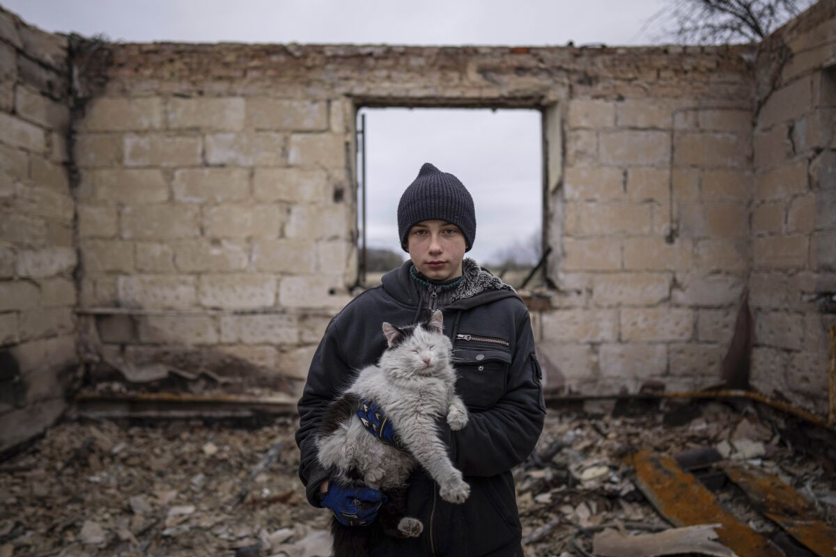 Danyk Rak, 12, holds a cat standing on the debris of his house destroyed by Russian forces' shelling in the outskirts of Chernihiv, Ukraine, Wednesday, April 13, 2022. After shelling Danyk's mother Liudmila Koval had to have her leg amputated and was injured in her abdomen. She is still waiting for proper medical treatment. (AP Photo/Evgeniy Maloletka)