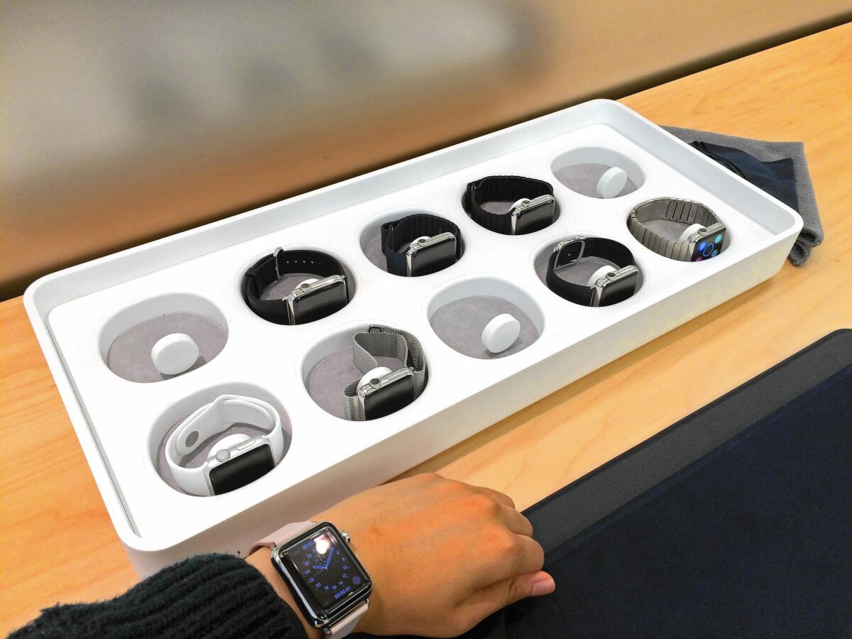 Los Angeles Times reporter Tracey Lien tries on the Apple Watch at the Apple Store in Emeryville, Calif. Shoppers can choose from 10 watches, each nestled in a round pod inside a board game-sized box.