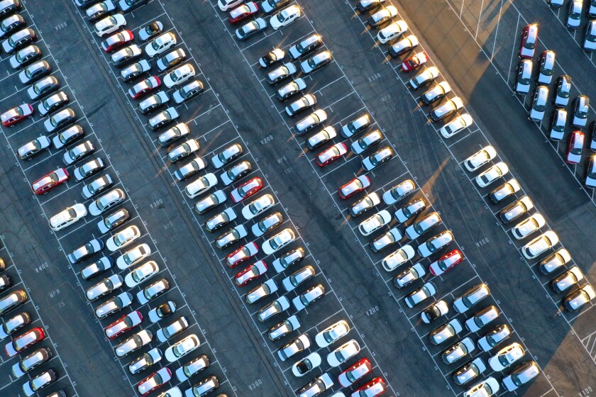 An aerial view of rows of new cars in a parking lot