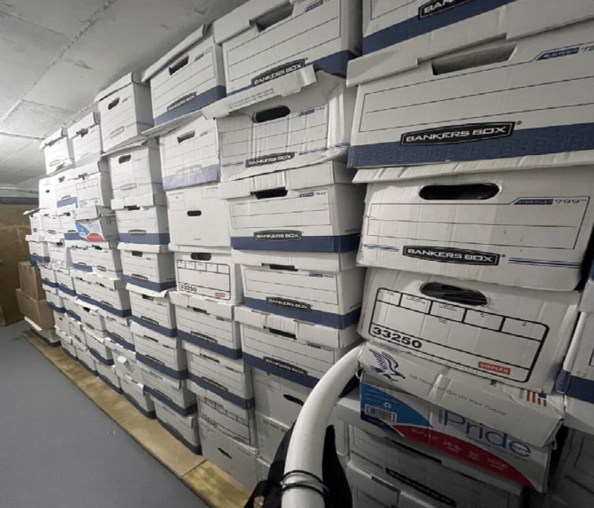 Dozens of white boxes stacked in a large storage room