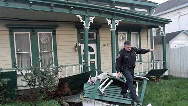 A Eureka Police officer walks across a damaged porch of a house that was knocked off its foundation after Saturday's earthquake.