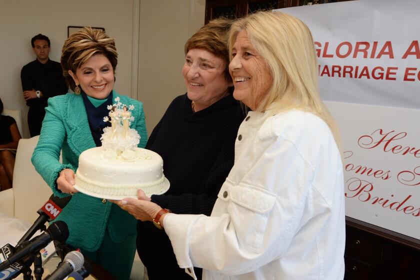Attorney Gloria Allred, left, passes a wedding cake to Robin Tyler, center, and her wife, Diane Olson, at a news conference in Los Angeles, after the U.S. Supreme Court issued decisions on California's Proposition 8 and the federal Defense of Marriage Act.