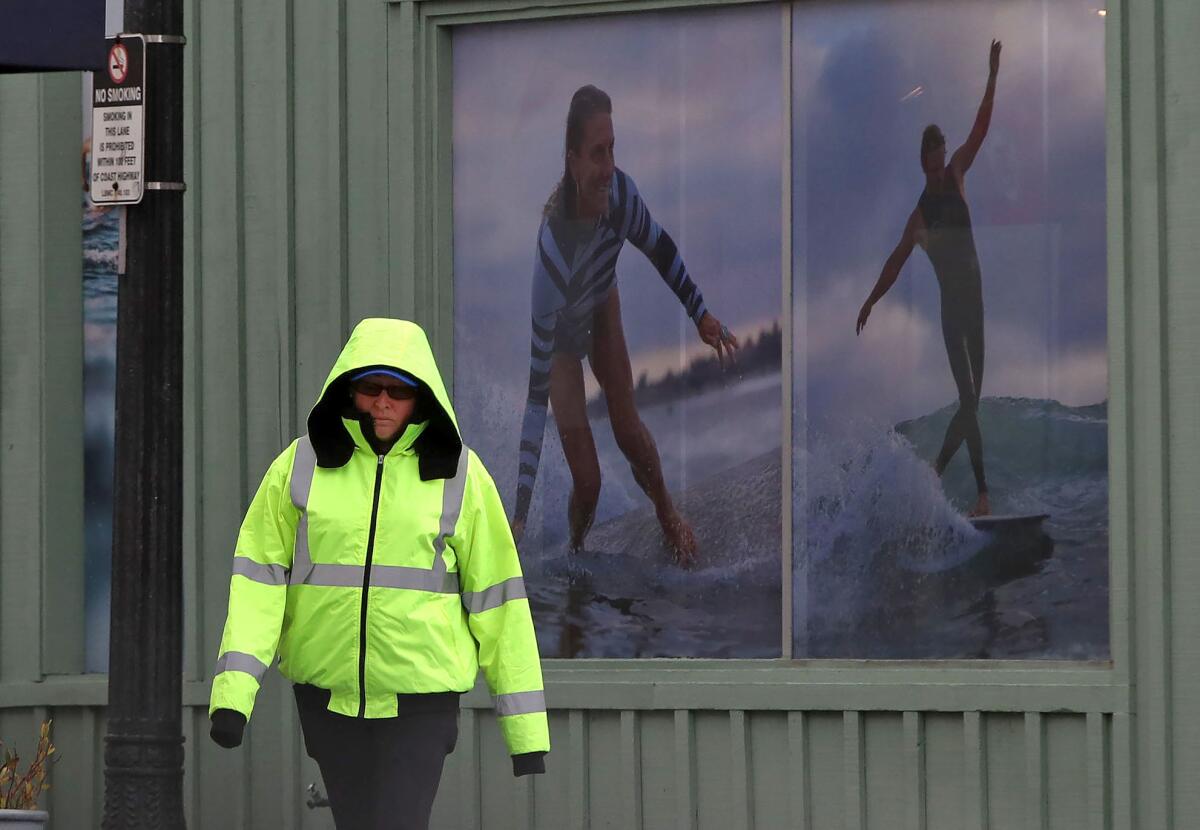 A woman is ready for the downpour as she walks in downtown Laguna Beach before the rain falls on Thursday afternoon.