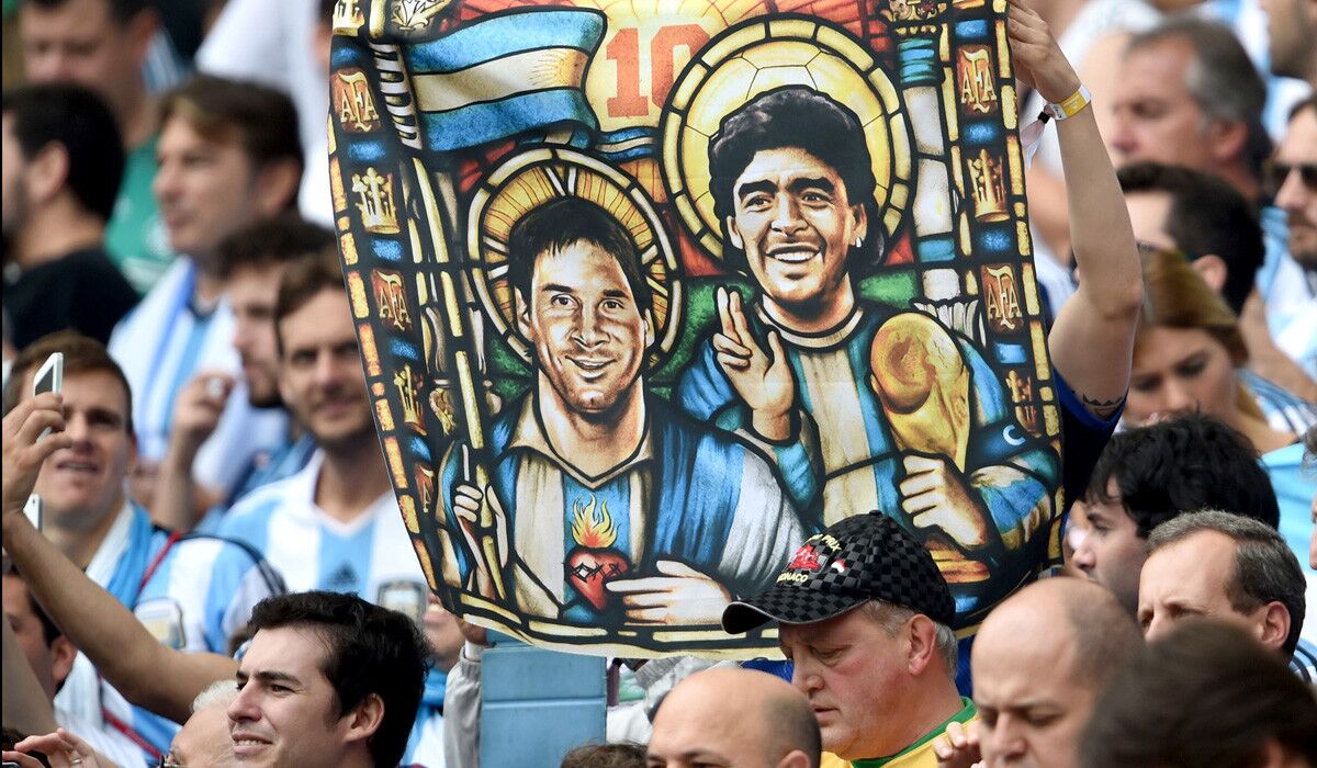 An Argentina fan holds an image depicting national team forward Lionel Messi and former World Cup star Diego Maradona as saints before a group game against Nigeria last week in Brazil.
