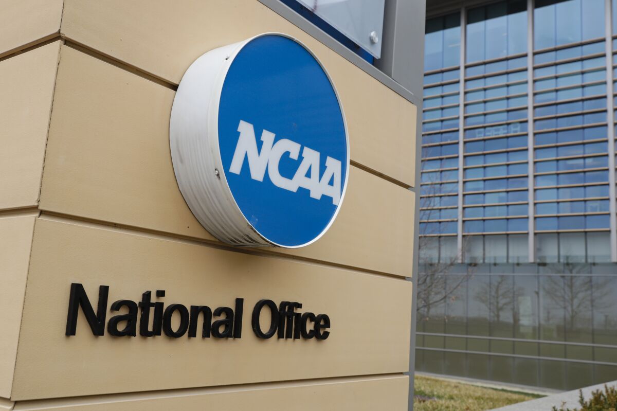 FILE - Signage at the headquarters of the NCAA is viewed in Indianapolis, March 12, 2020. By trying to limit how much schools can help college athletes cashing in on their fame, the NCAA seems to have inadvertently opened the door for boosters to get a foothold in a burgeoning market. (AP Photo/Michael Conroy, File)