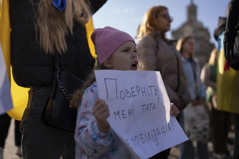 Liliia, who waits for her father to return from the frontline, holds a poster reading "Bring my father back. Demobilization!" while attending a meeting in Independence square in Kyiv, Ukraine, Friday, Oct. 27, 2023. Families of Ukrainian servicemen gathered to demand their loved ones return home after serving 18 months in the military as the war with Russia nears its second year. (AP Photo/Alex Babenko)