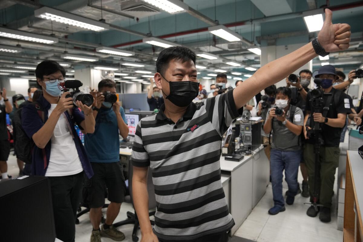 Lam Man-chung gives a thumbs-up in the Apple Daily newsroom as staffers take pictures and video.