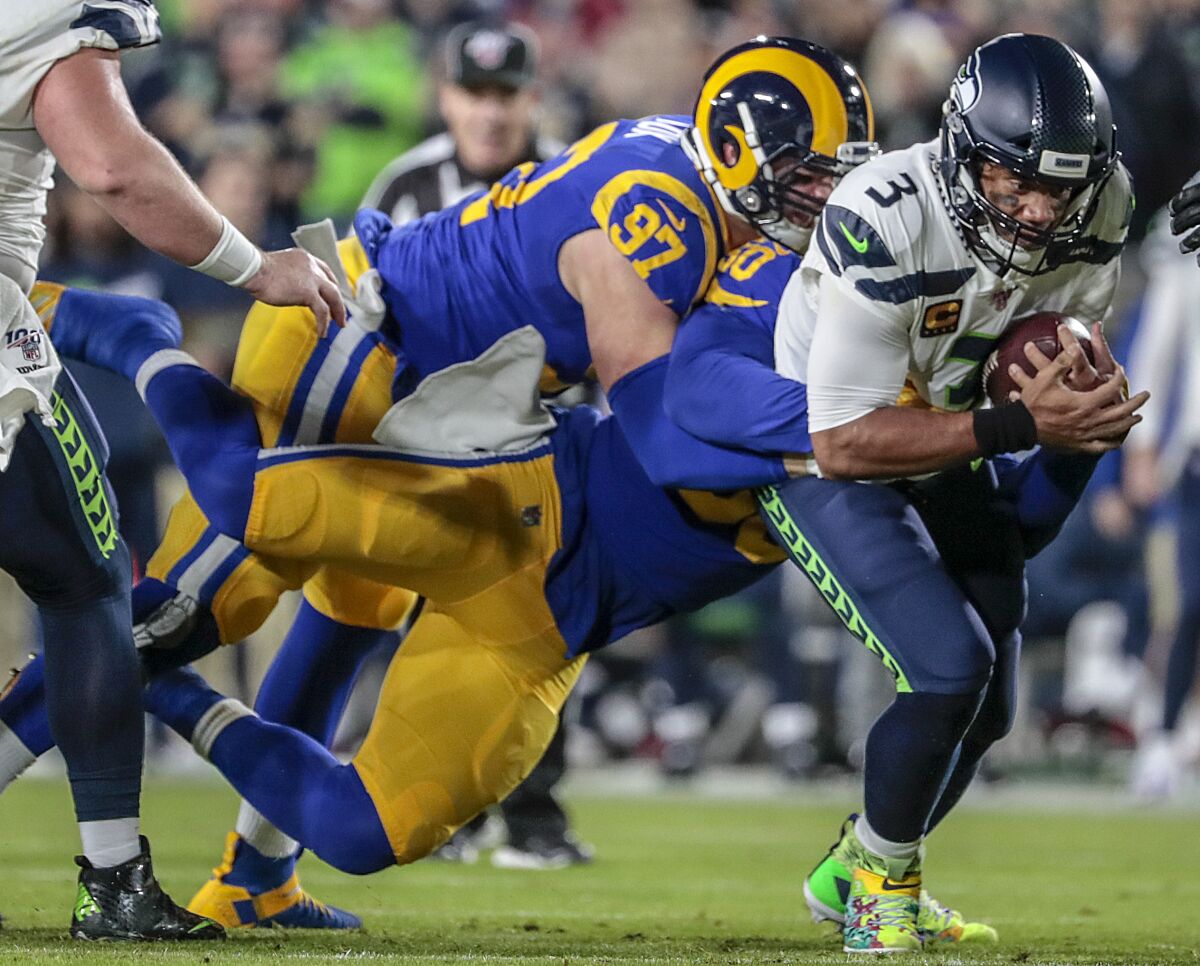 Seahawks quarterback Russell Wilson is sacked by Rams linebacker Samson Ebukam (50) and defensive end Morgan Fox in the first quarter.