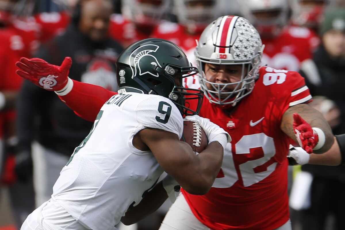 FILE - Ohio State defensive lineman Haskell Garrett, right, tackles Michigan State running back Kenneth Walker during the first half of an NCAA college football game Saturday, Nov. 20, 2021, in Columbus, Ohio. Garrett was selected to The Associated Press All-Big Ten team in results released Tuesday, Dec. 7, 2021. (AP Photo/Jay LaPrete, File)