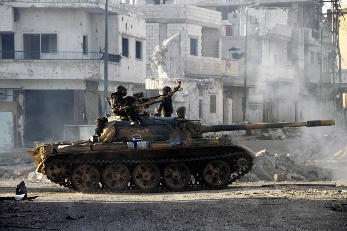 Syrian army troops drive through the ravaged streets of Qusair this week.