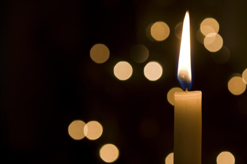 a single candle lit at night and in the background are light reflections