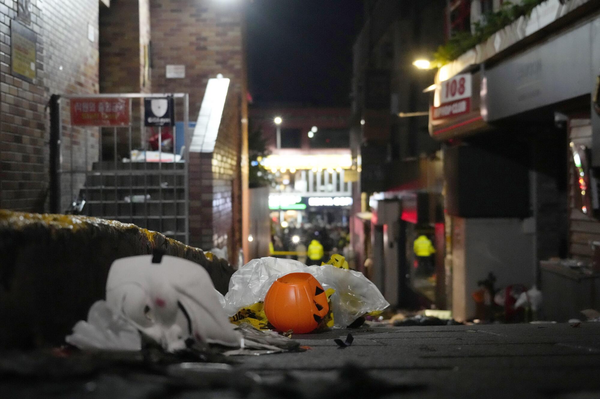 A jack-o'-lantern sits with other debris in an alley  