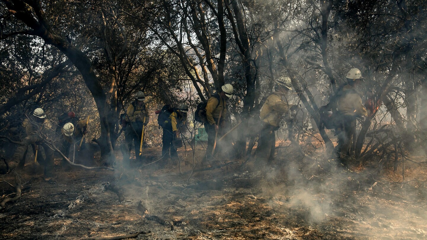 Firefighters clear brush while battling the Calgary fire in Wofford Heights, near Lake Isabella.