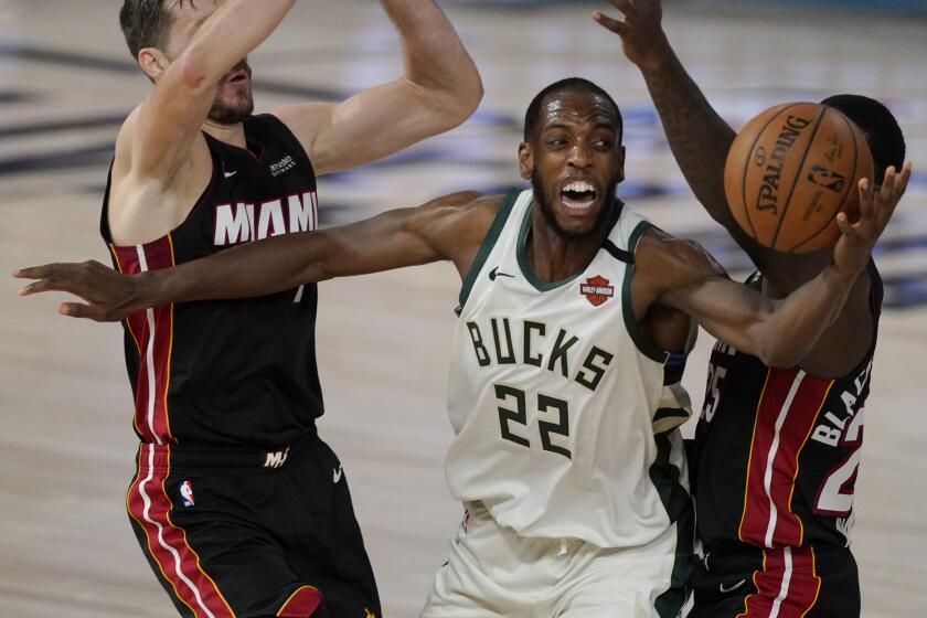 Milwaukee Bucks' Khris Middleton (22) is defended by Miami Heat's Goran Dragic, left, and Miami Heat's Kendrick Nunn, right, in the second half of an NBA conference semifinal playoff basketball game Tuesday, Sept. 8, 2020 in Lake Buena Vista, Fla. (AP Photo/Mark J. Terrill)