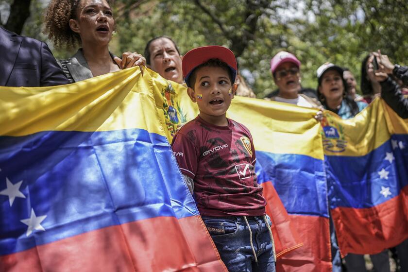 Manifestantes con una bandera venezolana se concentran en el consulado de Venezuela para protestar contra los resultados de las controvertidas elecciones presidenciales que dieron por ganador a Nicolás Maduro en Bogotá, Colombia, el jueves 1 de agosto de 2024. (AP Foto/Iván Valencia)