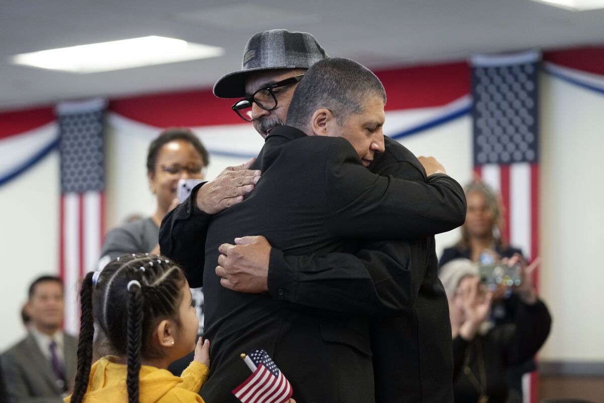 Deported veterans Mauricio Hernandez Mata, center right, and Leonel Contreras embrace after being sworn in as U.S. citizens at a special naturalization ceremony Wednesday, Feb. 8, 2023, in San Diego. Both Army veterans, the two men were among 65 who have been allowed back into the United States nearly a year ago as part of a growing effort by the U.S. government to recognize the service of immigrants who served in the U.S. military only to wind up deported. (AP Photo/Gregory Bull)