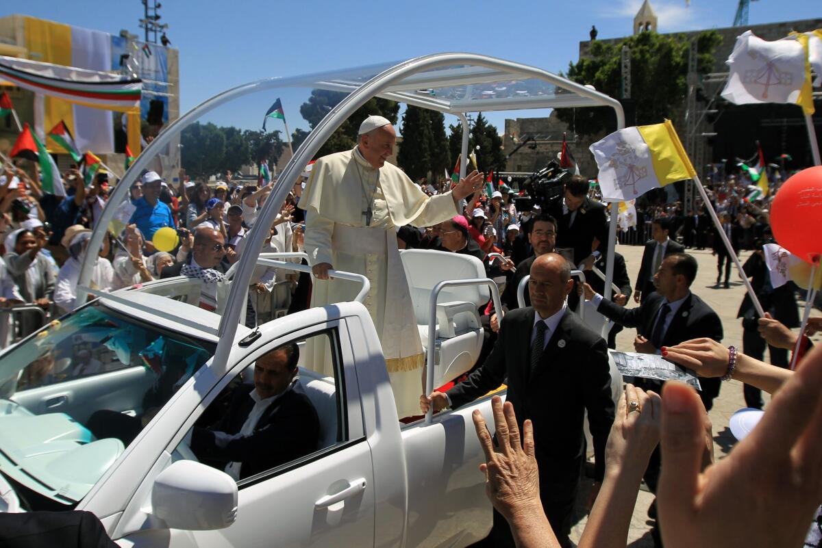 Pope Francis waves to the crowd as he arrives at Manger Square before presiding over an open-air Mass outside the Church of the Nativity in Bethlehem.