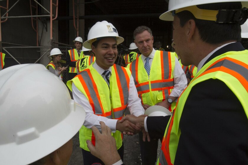 U.S. Housing and Urban Development Secretary Julian Castro, left, greeted San Diego City Councilman Todd Gloria (right) while Rep. Scott Peters watched before going on a tour of the Hotel Churchill, which is being converted into affordable housing units.