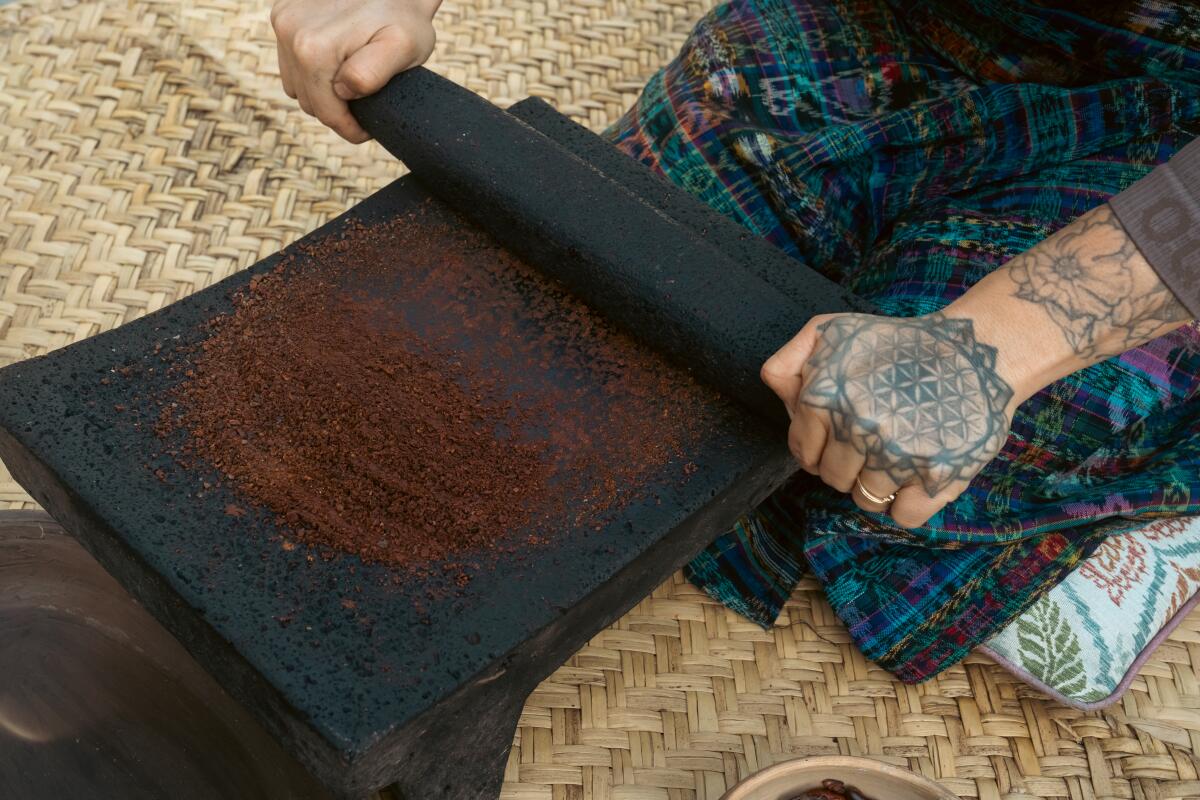 Once peeled, small amounts of cacao seeds at a time are grinded on a traditonal metate made of volcanic rock.