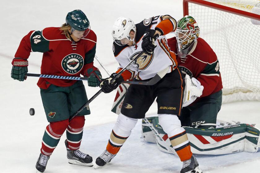 Ducks’ Corey Perry, center, has problems getting to the puck as Minnesota’s Mikael Granlund, left, helps goalie Devan Dubnyk defend the net on Saturday.