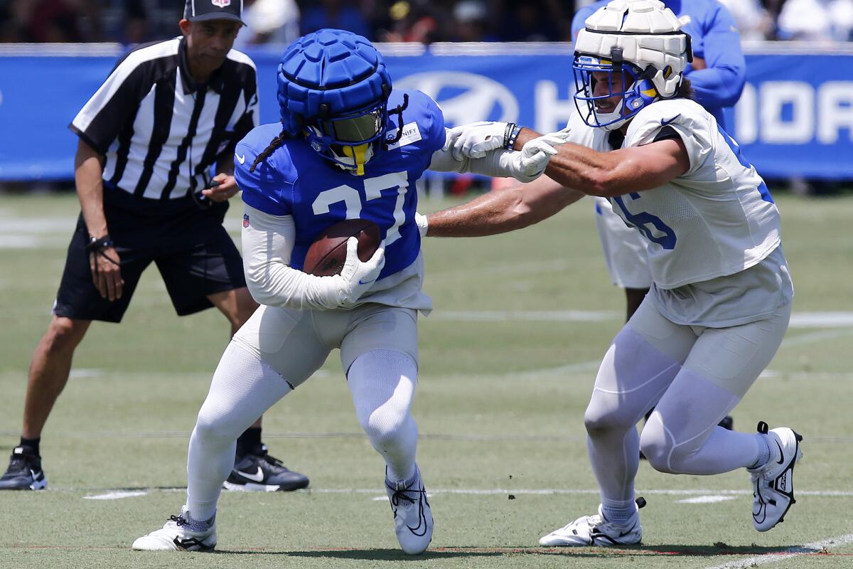 Running back Darrell Henderson Jr., left, carries the ball against linebacker Christian Rozeboom during Friday's practice.