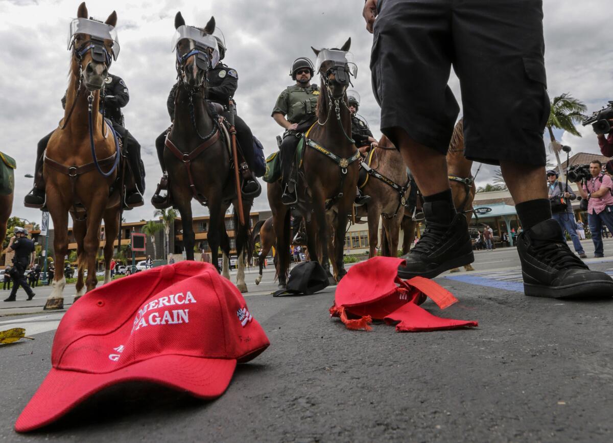 A protester stomps on Donald Trump "Make America Great Again" baseball caps on the ground behind the Anaheim Convention Center while a Trump campaign rally is underway in May.