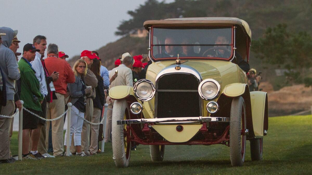 Spectaors watch a 1917 Moon 6-45 Roadster drive onto the Pebble Beach lawn.