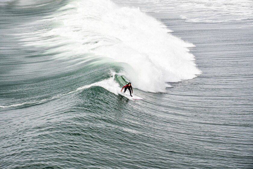 A surfer rides a wave near the Oceanside Pier.