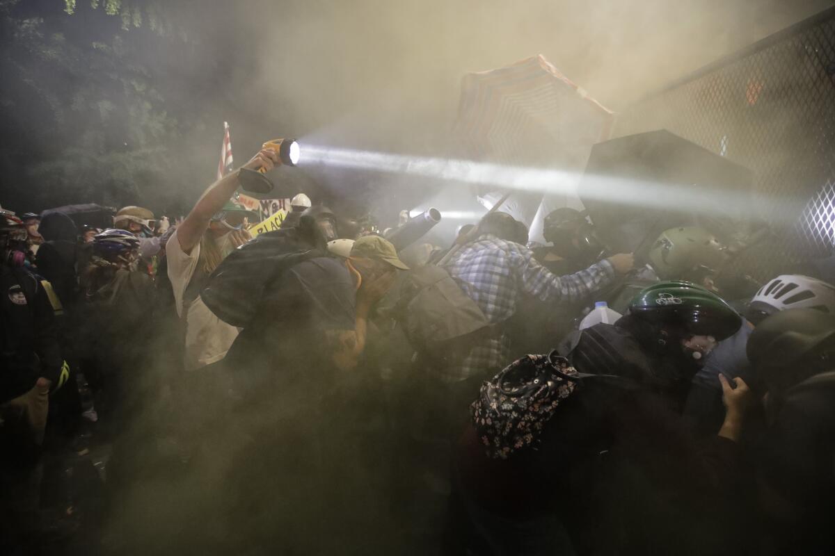 Demonstrators push on a fence as tear gas is deployed during a Black Lives Matter protest