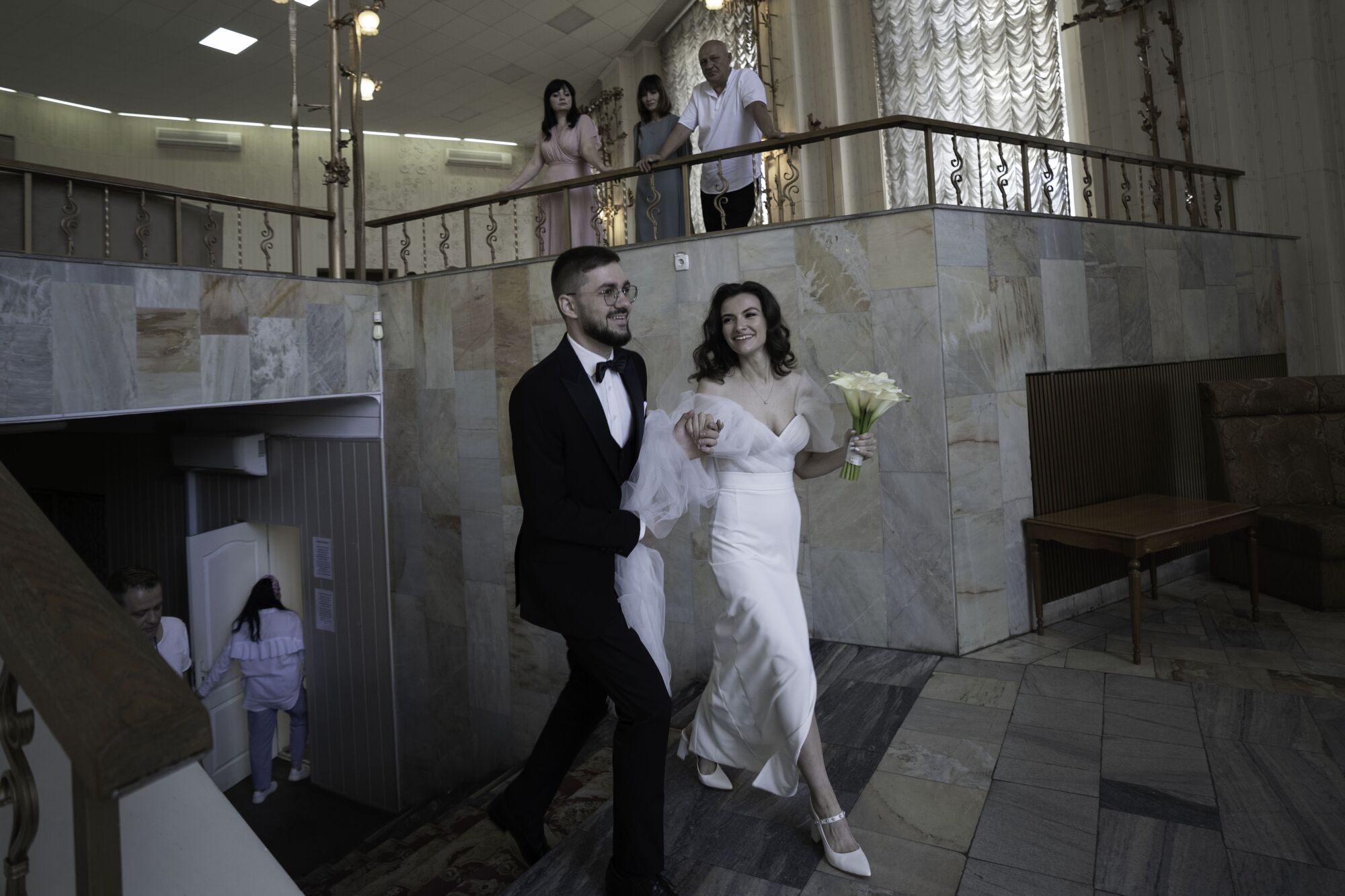 A smiling bride and groom walk to a hall