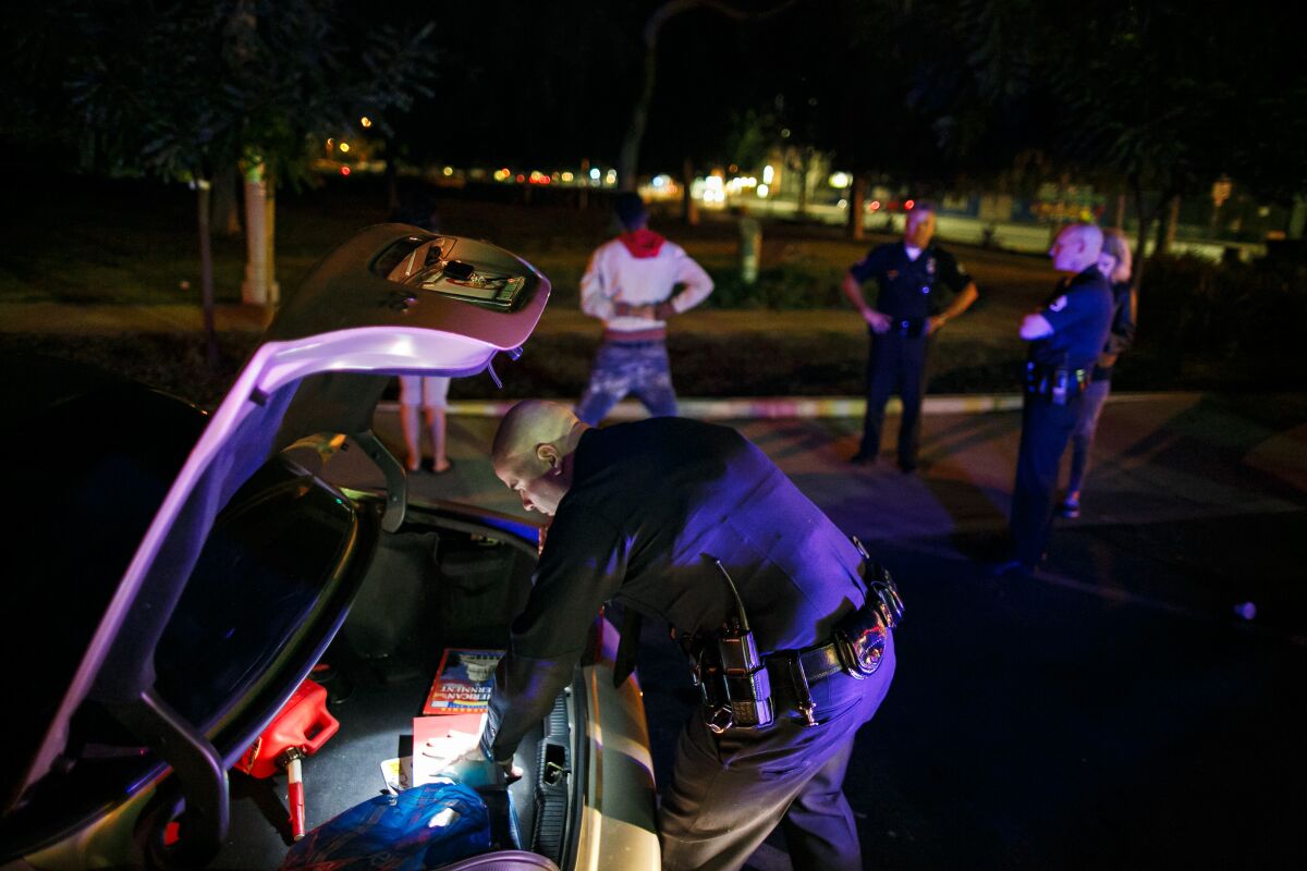 A police officer inspects the trunk of a vehicle during a stop.