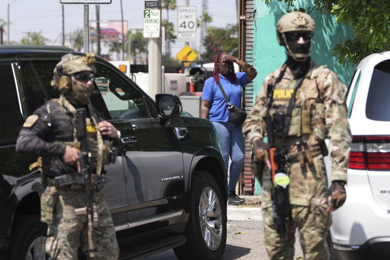 A bystander watches as immigration agents conduct an operation at a car wash on Friday, Aug. 15, 2025, in Montebello, Calif. (AP Photo/Gregory Bull)