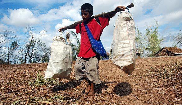 A young boy carries bags of salvaged material from cyclone debris