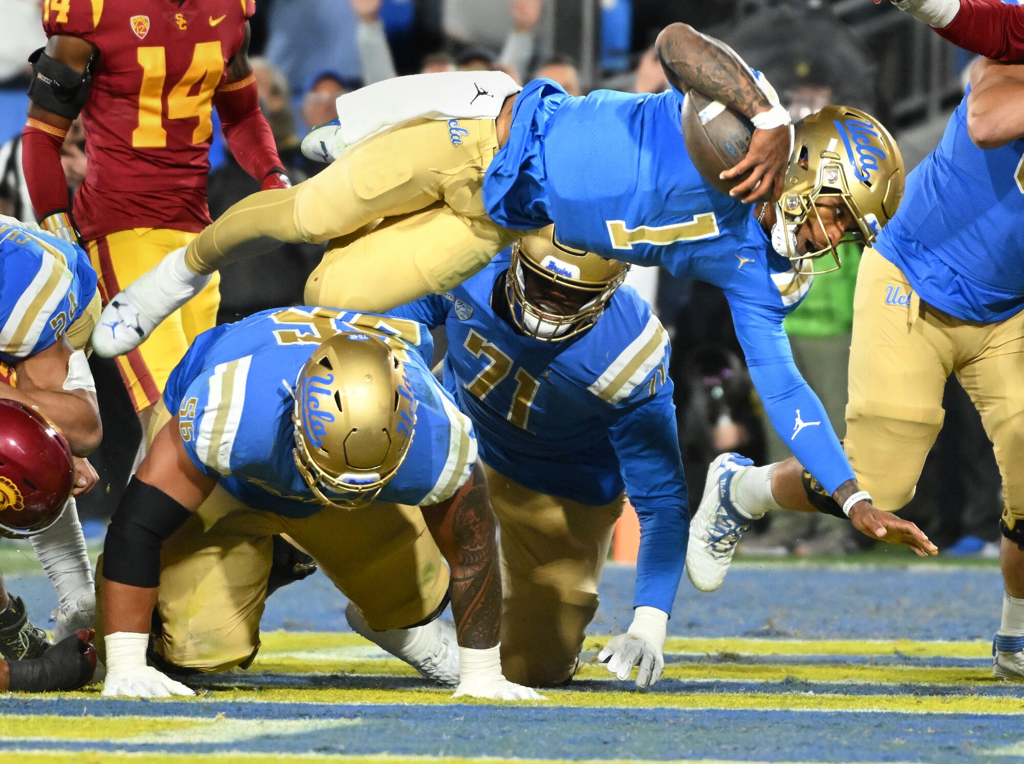 UCLA quarterback Dorian Thompson-Robinson dives over teammates to score a touchdown against USC 