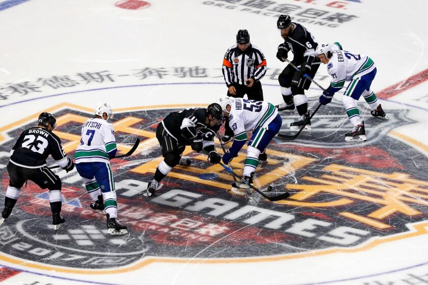 The Kings and Canucks fight for the puck during a preseason game at Mercedes-Benz Arena in Shanghai on Sept. 21, 2017.